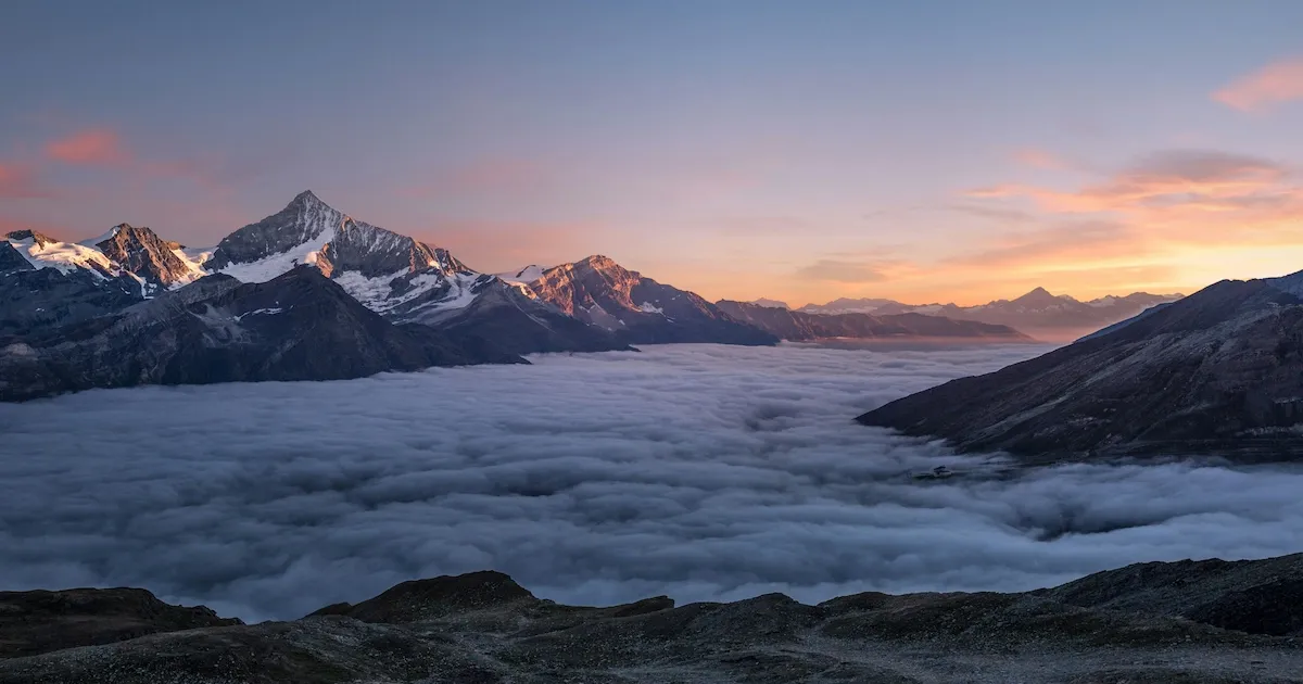 Snowy mountains in a sea of clouds at sunset